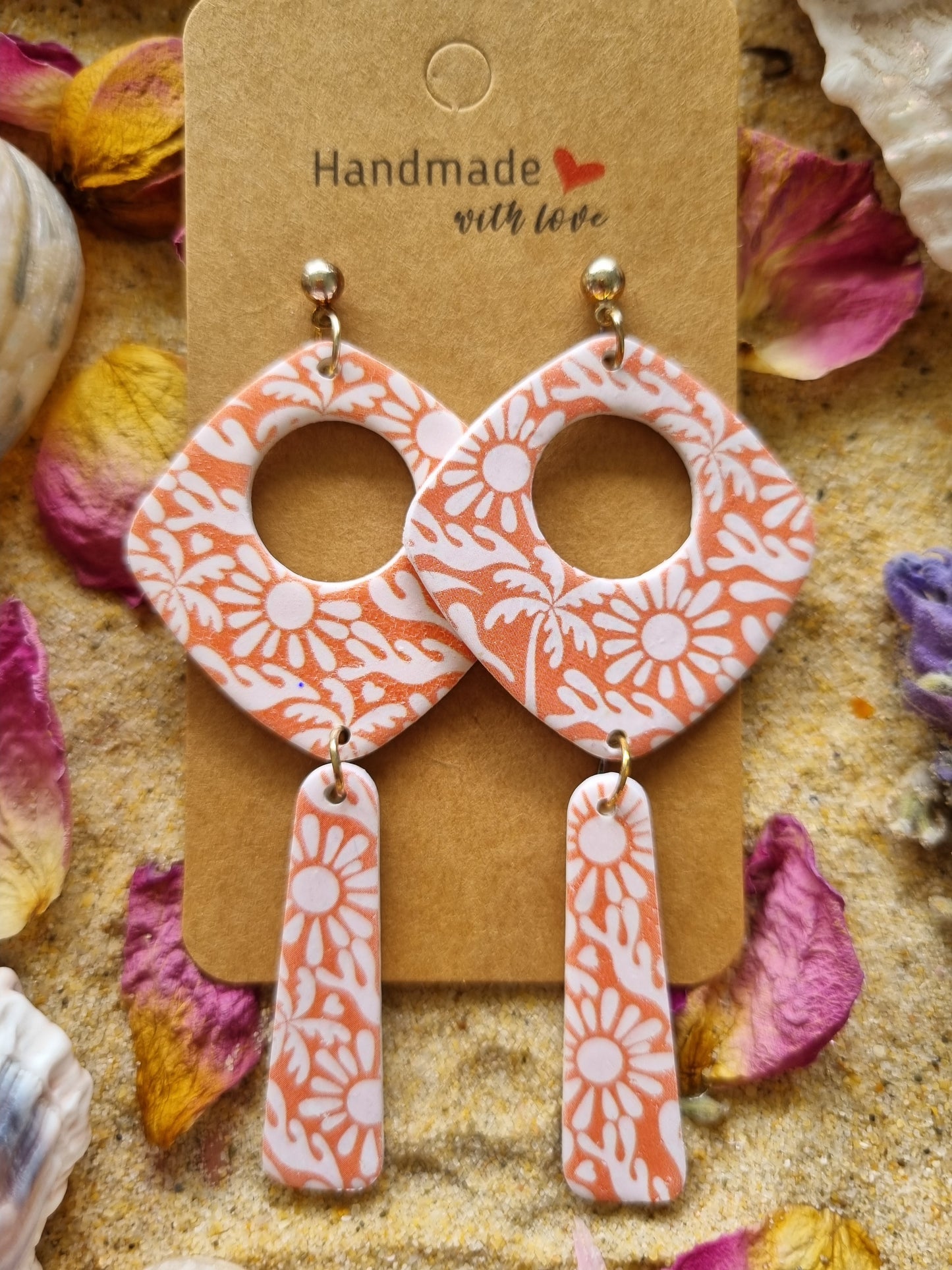 Handmade polymer-clay dangle earrings featuring cream daisies & tropical palms on a tangerine background